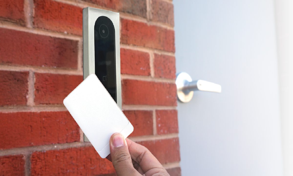 Resident tapping a key card credential on a CellGate Entría reader mounted on a brick building exterior