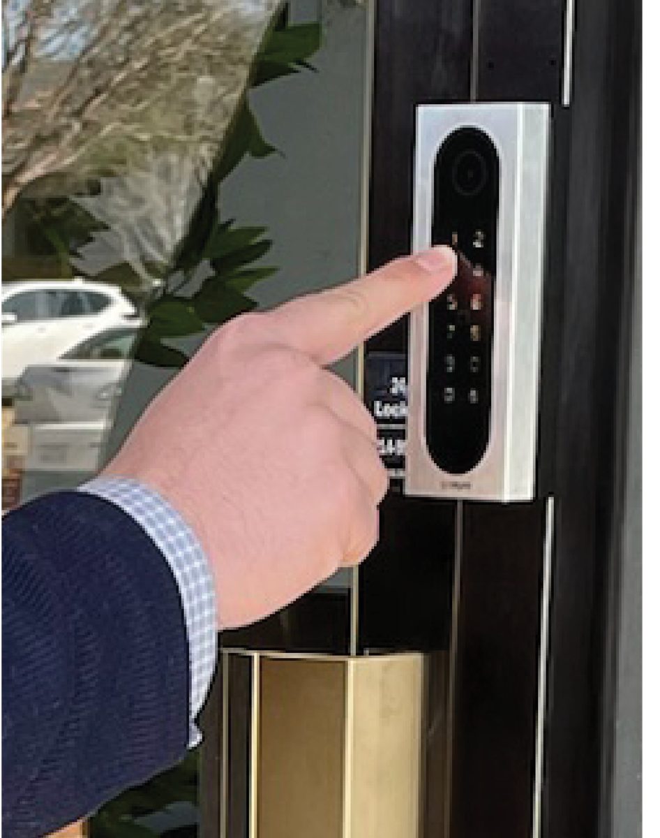 Person entering a code on a CellGate Entría keypad controller mounted beside a glass office entry door